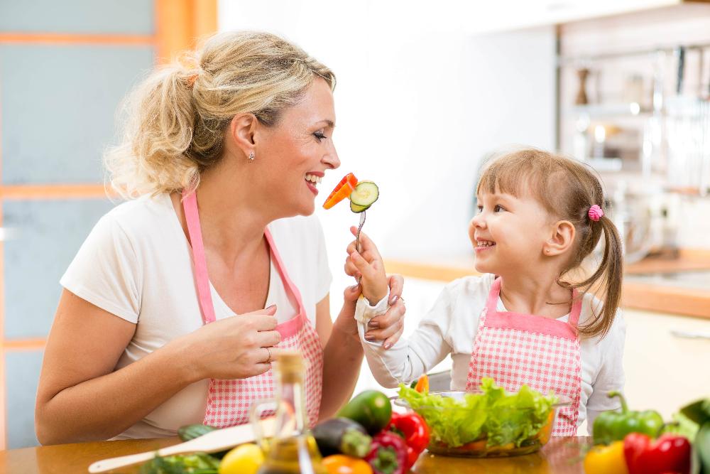 child feeds mother vegetables