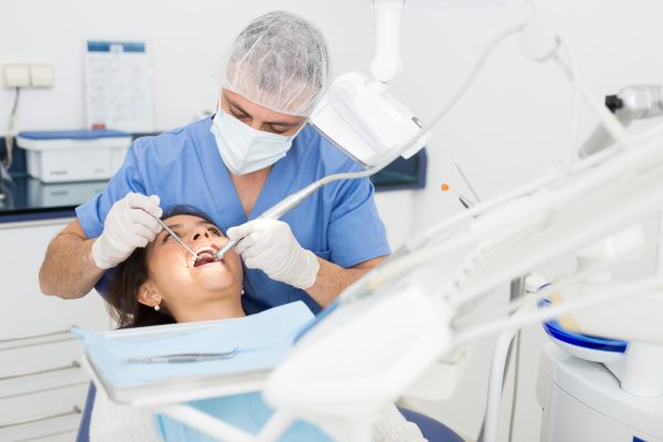 male dentist working on a patient's teeth at a a dental office