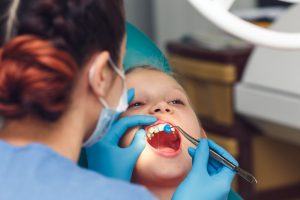 dentist perform fluoride treatment on child